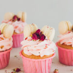 Pink Macaroon Cupcakes; fun pink valentines day cupcakes with edible roses and macaroon cookies! Delicate delicious cupcakes with pink cream, macaroons, and roses for Valentine's day.