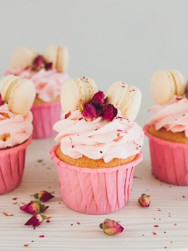 Pink Macaroon Cupcakes; fun pink valentines day cupcakes with edible roses and macaroon cookies! Delicate delicious cupcakes with pink cream, macaroons, and roses for Valentine's day.