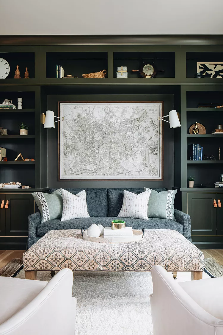 Dark green built-in bookshelves with sofa, large wall map, and decorative accents