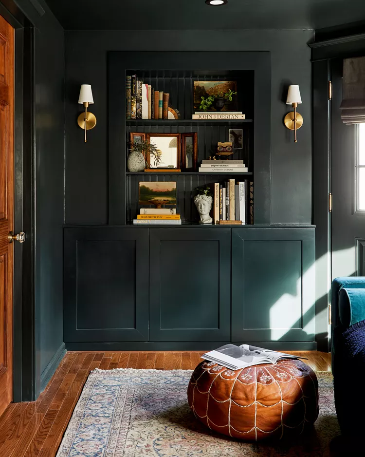 Dark built-in bookshelf with brass sconces, styled books, and decorative accents
