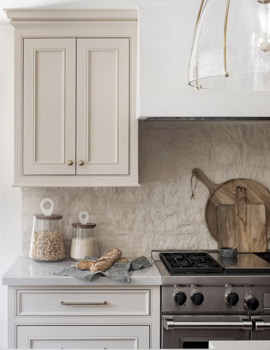 Kitchen with a natural stone backsplash featuring minimal grout lines, white cabinetry, and a seamless countertop-to-backsplash transition.
