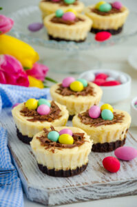 Easter Brownie Cheesecake Birds Nests; brownie crust, creamy cheesecake filling topped with mini eggs for a delicious Easter dessert recipe! Easter mini brownie cheesecake Bird's Nest with chocolate and candy eggs. Easter dessert. Funny food idea for children.
