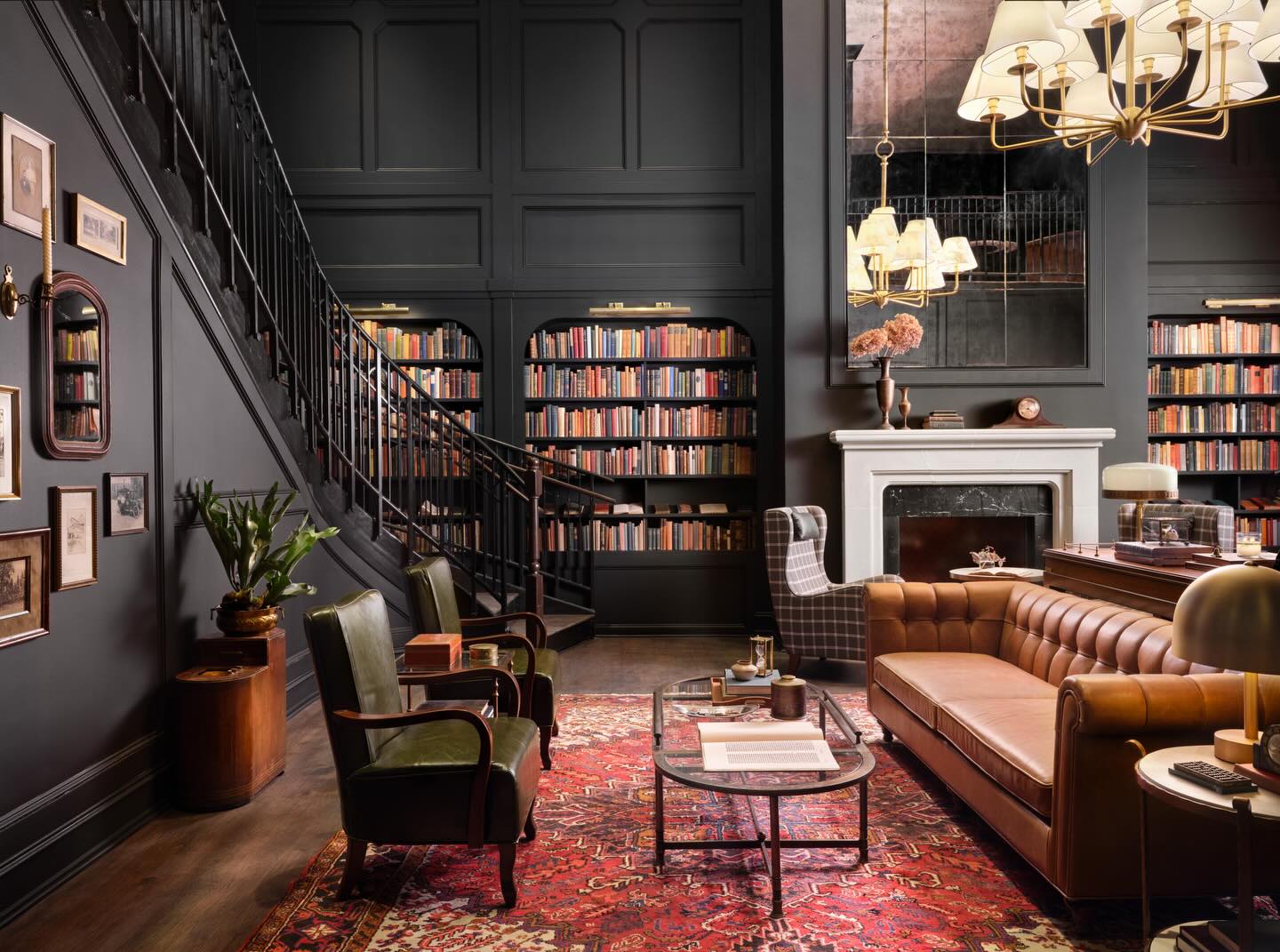 Moody living room by Joanna Gaines featuring dark paneled walls, built-in bookshelves, leather sofa, vintage rug, and classic fireplace.