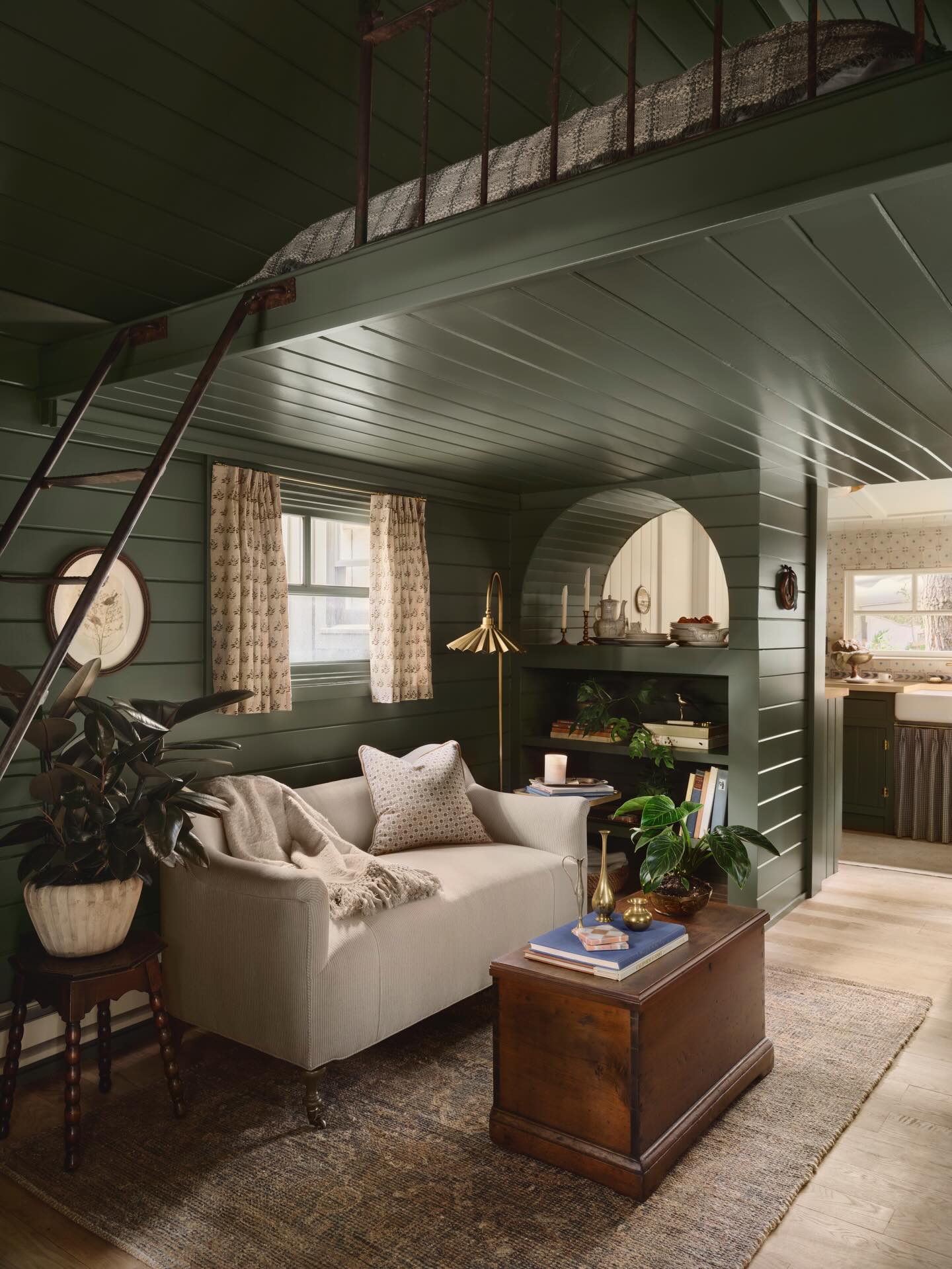 Green living room by Joanna Gaines featuring built-in shelving, cozy sofa, vintage wood coffee table, and charming farmhouse details.