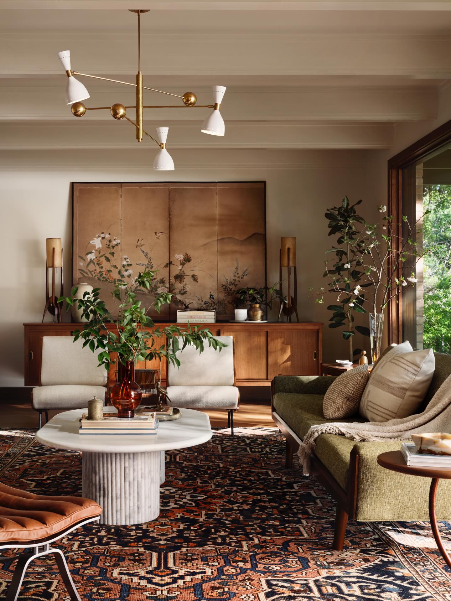 Midcentury-inspired living room by Joanna Gaines featuring a patterned rug, sculptural lighting, warm wood furniture, and layered neutral decor.