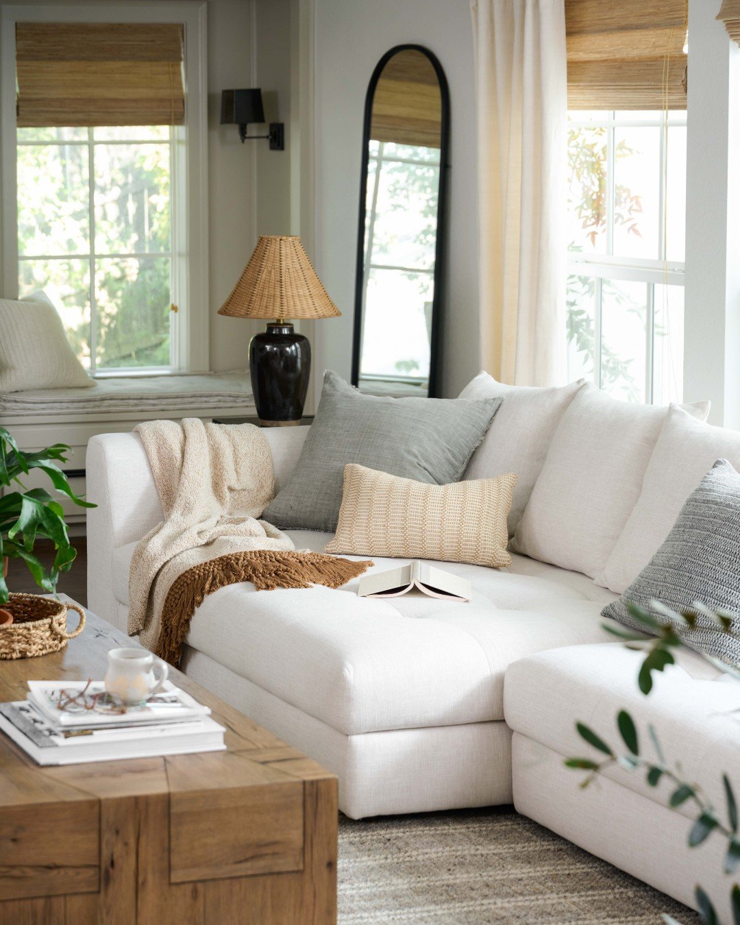 Neutral living room by Joanna Gaines featuring a soft white sectional, layered throw pillows, wood coffee table, and warm farmhouse decor.