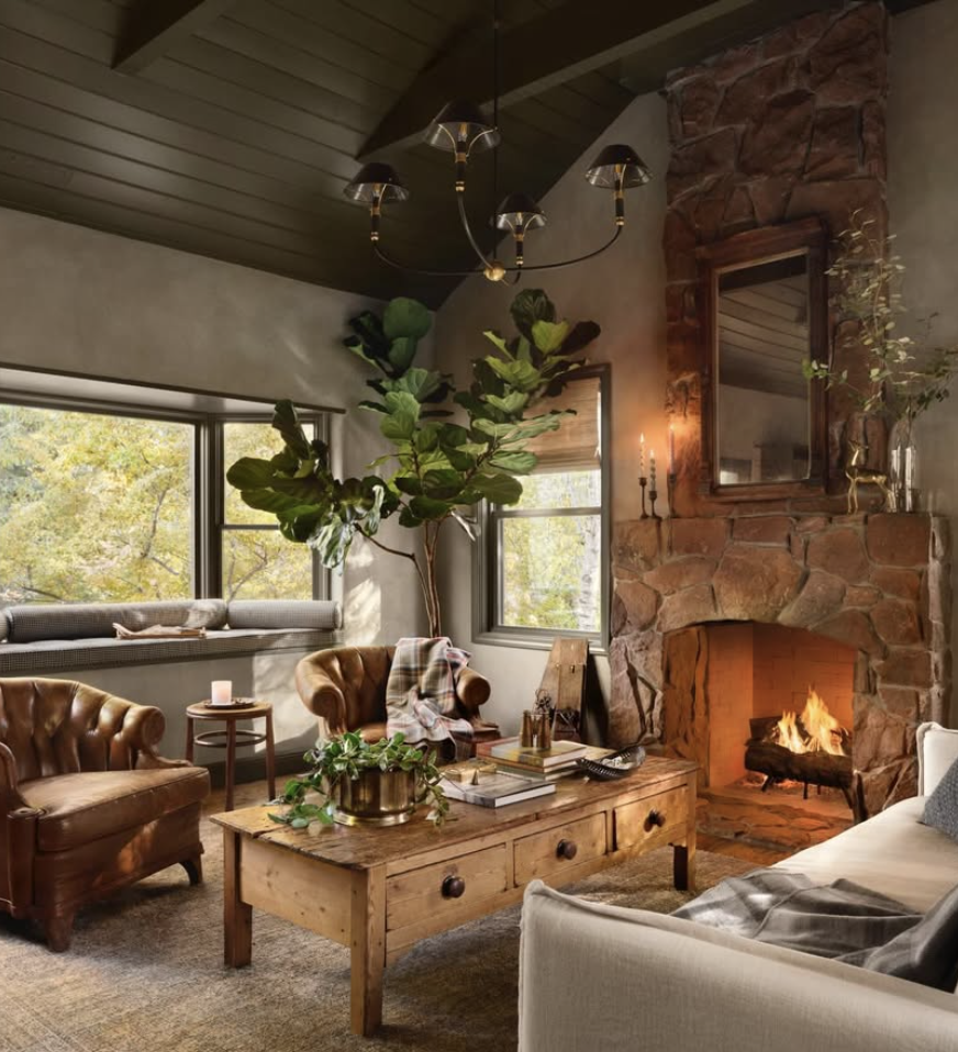 Rustic cabin living room by Joanna Gaines featuring a stone fireplace, leather accent chairs, wood coffee table, and cozy farmhouse decor.