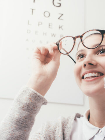 Lens replacement: Happy young woman trying her new glasses, eye care concept