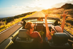 3-Day American Road Trip Ideas For The Ultimate Travel Experience - Happy Young Carefree Couple Driving Along Country Road in Convertible at Sunset