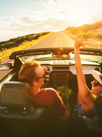 3-Day American Road Trip Ideas For The Ultimate Travel Experience - Happy Young Carefree Couple Driving Along Country Road in Convertible at Sunset