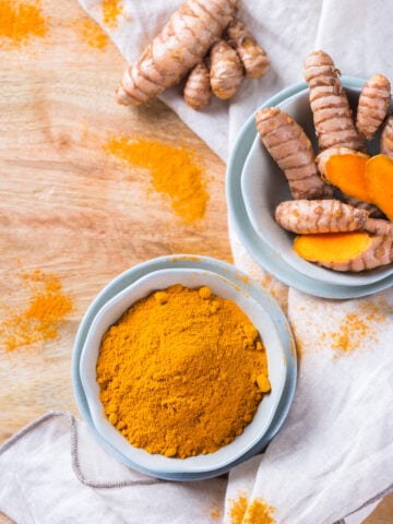 Benefits of Turmeric; Food and drink, diet nutrition, health care concept. Raw organic orange turmeric root and powder, curcuma longa on a cooking table. Indian oriental low cholesterol spices.