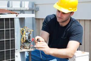 Young repairman fixing an industrial air conditioning compressor. - Why is Professional AC Installation Important?