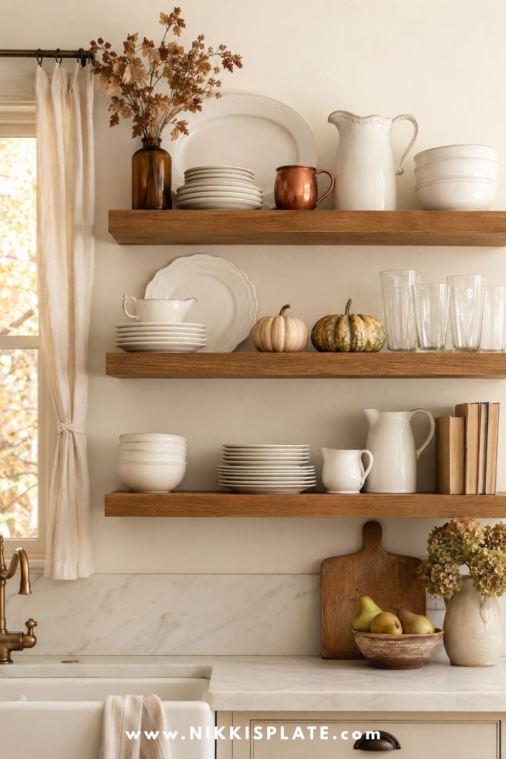 Warm oak kitchen shelves decorated for fall with white ironstone dishes, amber glass, copper mugs, mini pumpkins, pears and dried seasonal flowers.