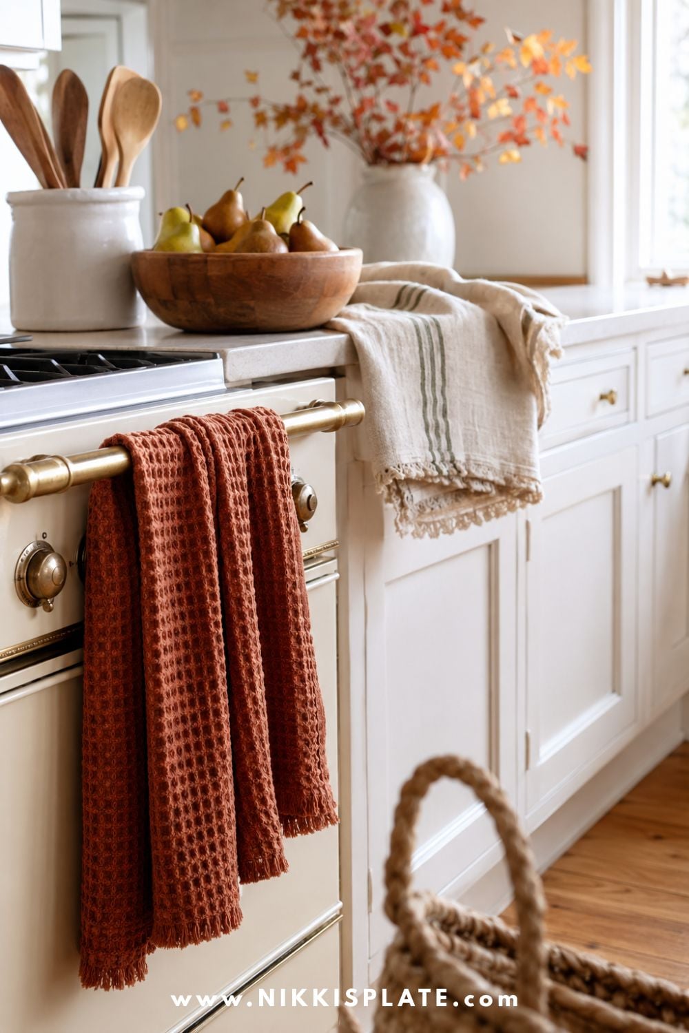 Muted rust waffle-weave and oatmeal striped fall kitchen towels adding soft seasonal color and texture to a bright white farmhouse kitchen.
