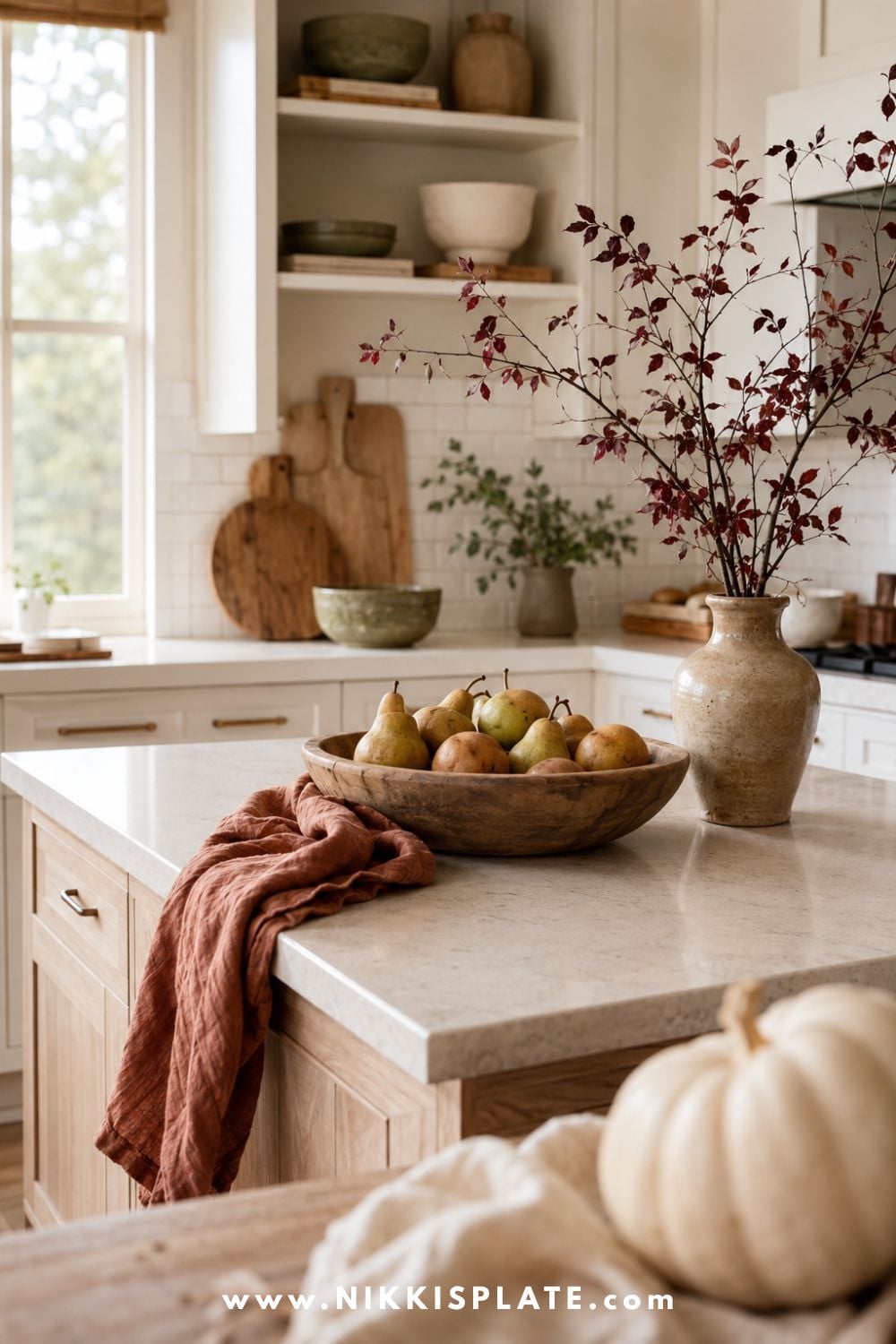 Bright farmhouse kitchen styled with a warm autumn color palette of cream, rust, olive, caramel and burgundy through seasonal linens, pottery and fall branches.