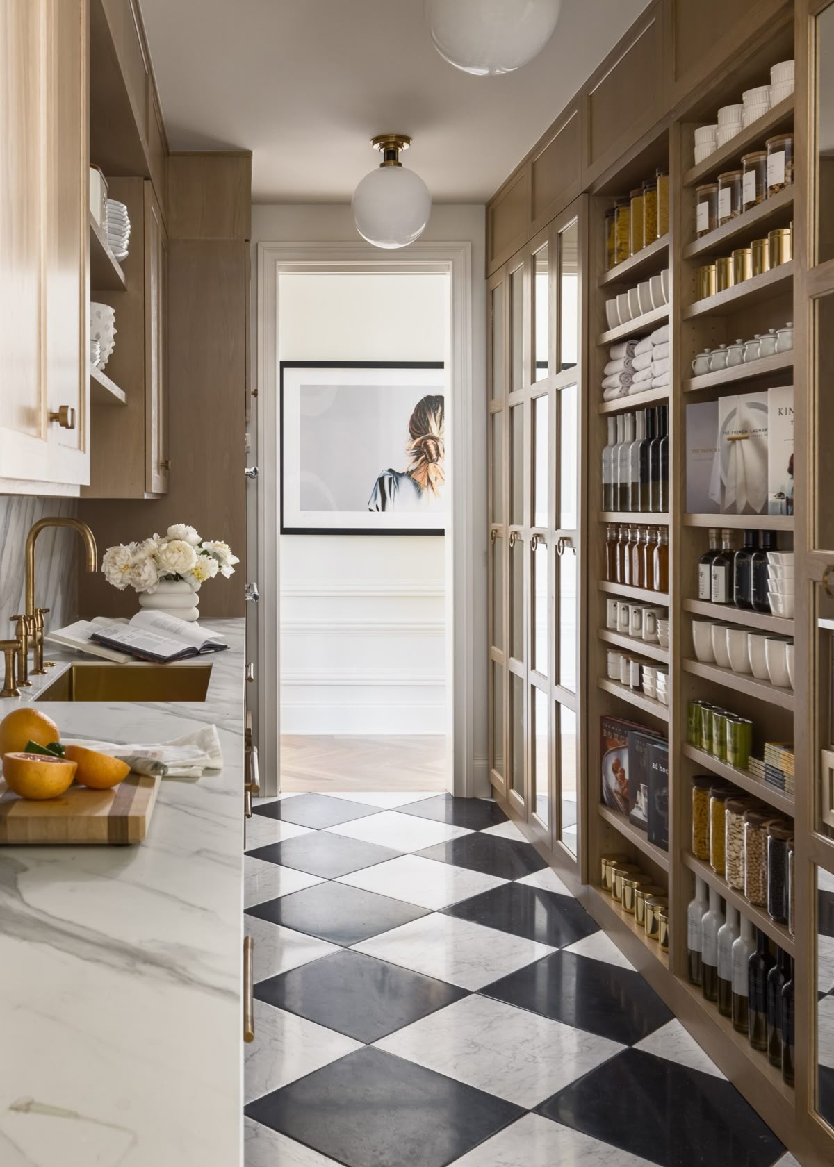Butler's pantry with built-in wood cabinetry, glass-front cabinets, marble countertops, and organized storage showcasing a popular kitchen trend for 2026.