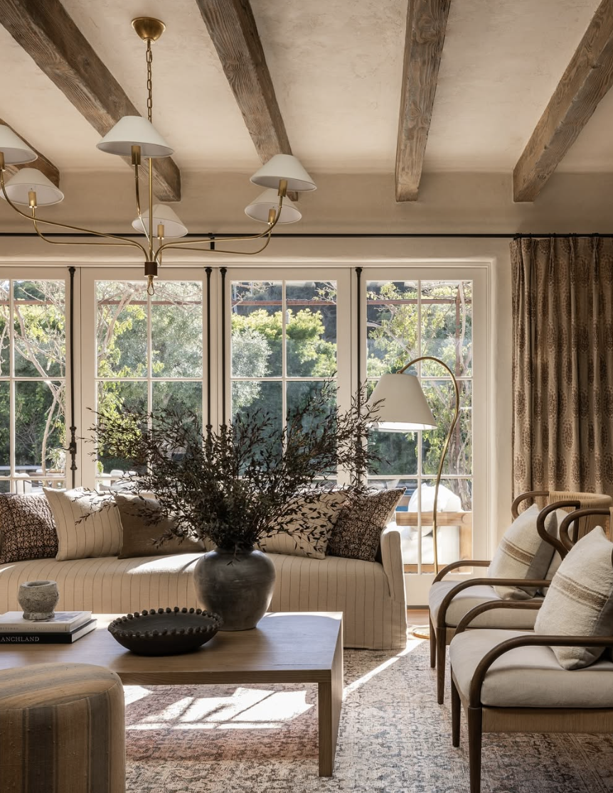 Conversation-focused living room layout with seating arranged for connection, warm neutral furniture, layered lighting, and natural textures, reflecting living room trends for 2026.