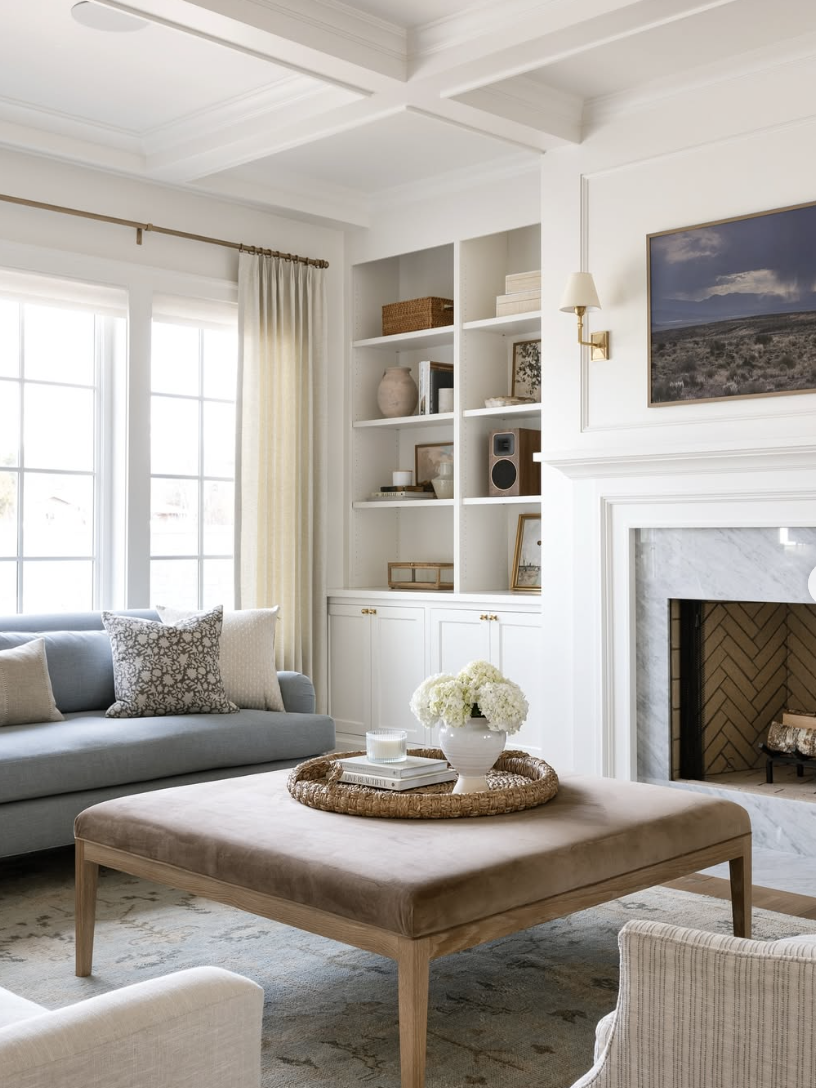 Living room featuring natural materials like stone, linen, and wood with a cozy neutral palette, built-in shelving, and layered textures, showcasing living room trends for 2026.