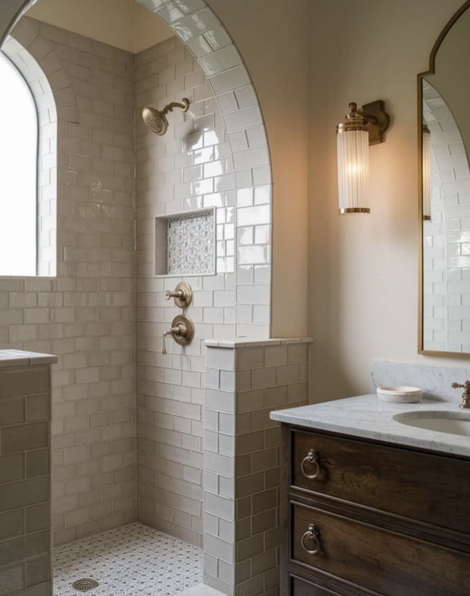 Soft, mood-boosting bathroom lighting with warm sconces and arched walk-in shower showcasing bathroom trends for 2026 with a calm, spa-like atmosphere