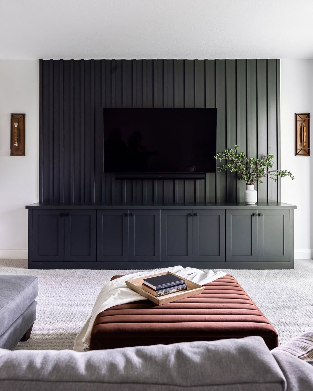 Built-in basement storage and custom millwork featuring sleek cabinetry, vertical slat accent wall, and a modern media setup, showcasing basement trends for 2026