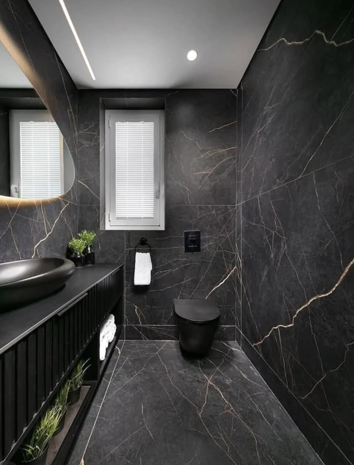 Black marble tile bathroom floor paired with dark marble walls, matte black fixtures, and a sleek modern vanity.