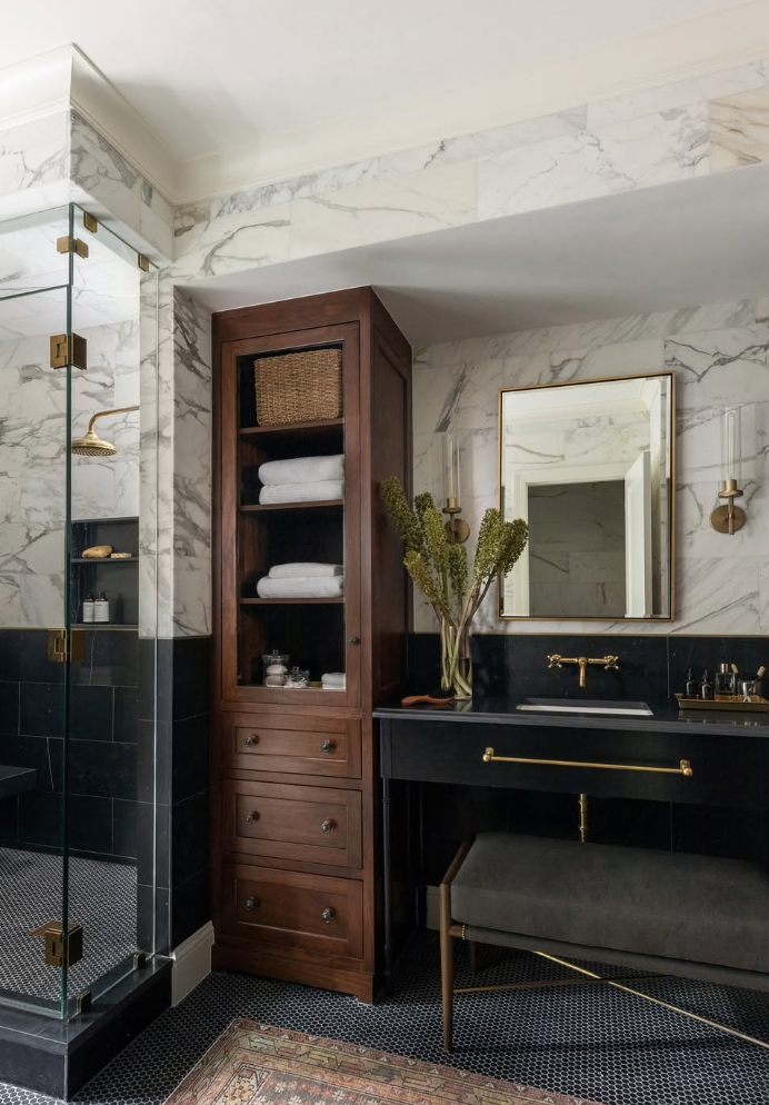 Black mosaic tile bathroom floor paired with marble walls, a dark vanity, and brass fixtures in a luxury bathroom.