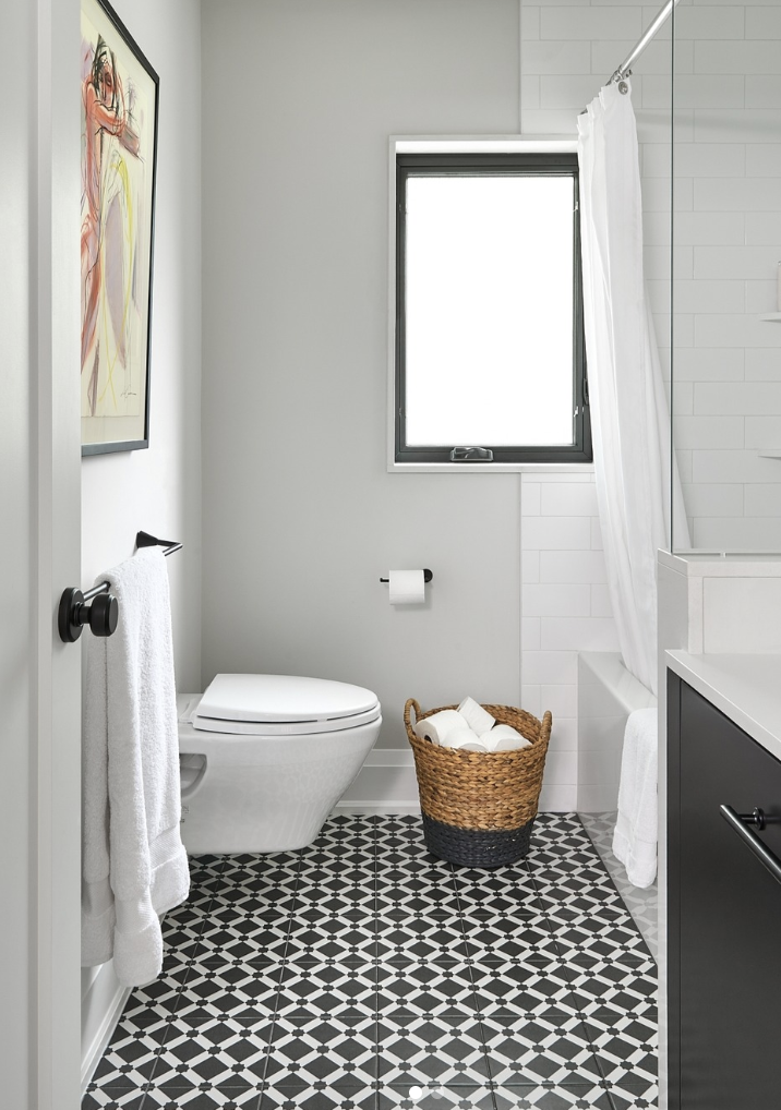 Black patterned tile bathroom floor paired with white walls, a floating vanity, and a bright, modern bathroom layout.