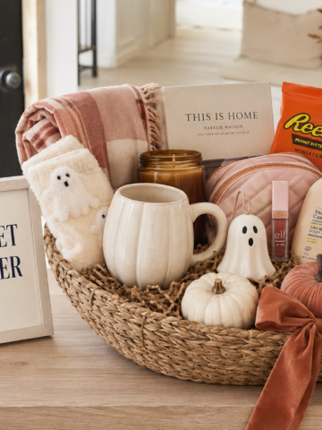 Boo basket ideas for her featuring cozy socks, beauty products, Halloween candy, gift cards, a pumpkin mug and fall accessories.