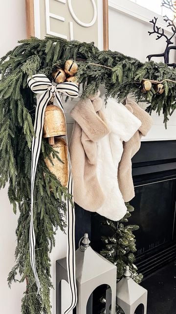 This chic mantel design combines modern elegance with timeless Christmas charm. A striped black and white ribbon tied into a bow adds a crisp contrast against lush greenery and gold bells, while soft faux fur stockings bring warmth and texture. A stylish take on Christmas ribbon ideas for holiday decor that feels both cozy and sophisticated.