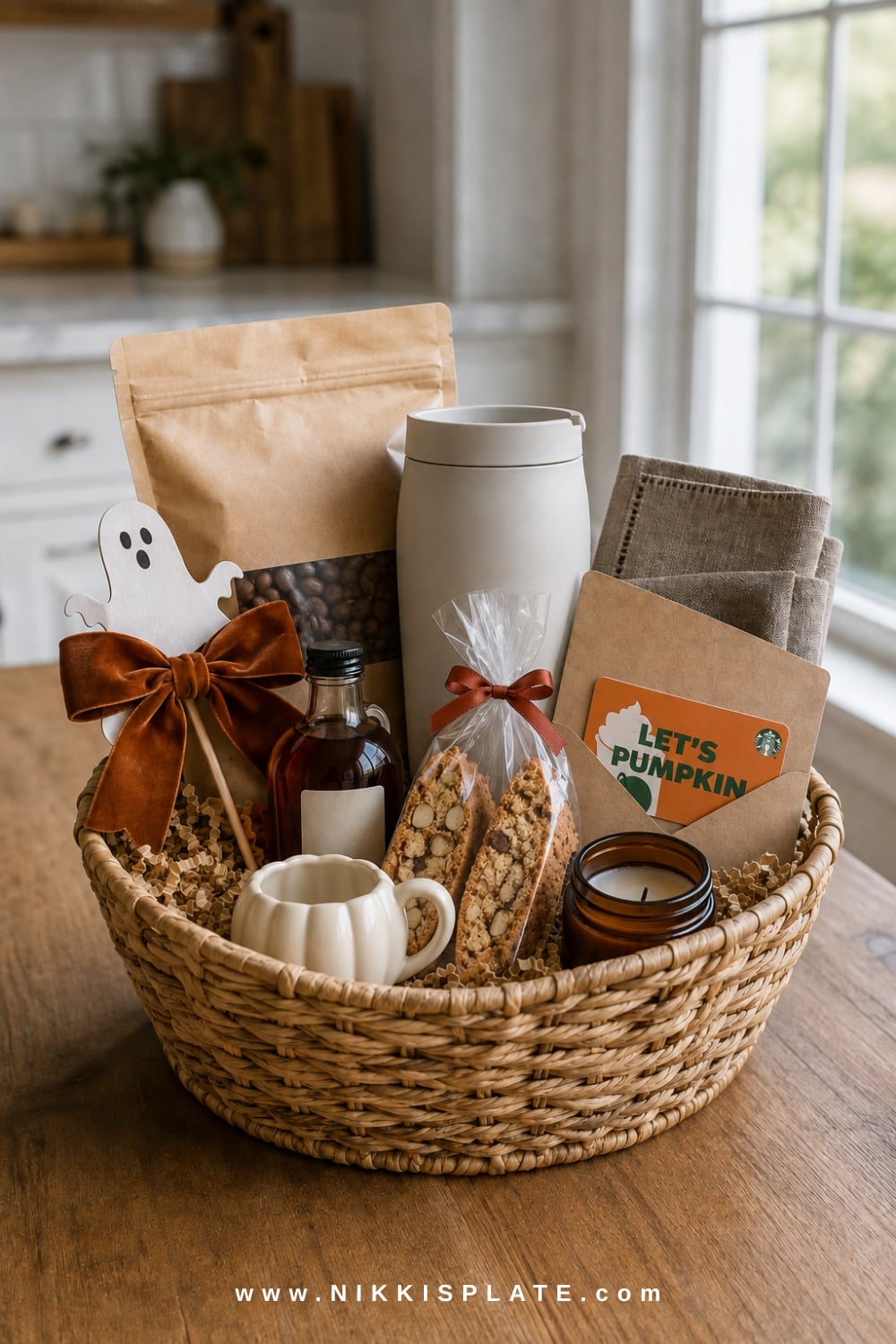 Coffee lover's boo basket with beans, a cream travel tumbler, maple syrup, biscotti, chocolate and a candle.