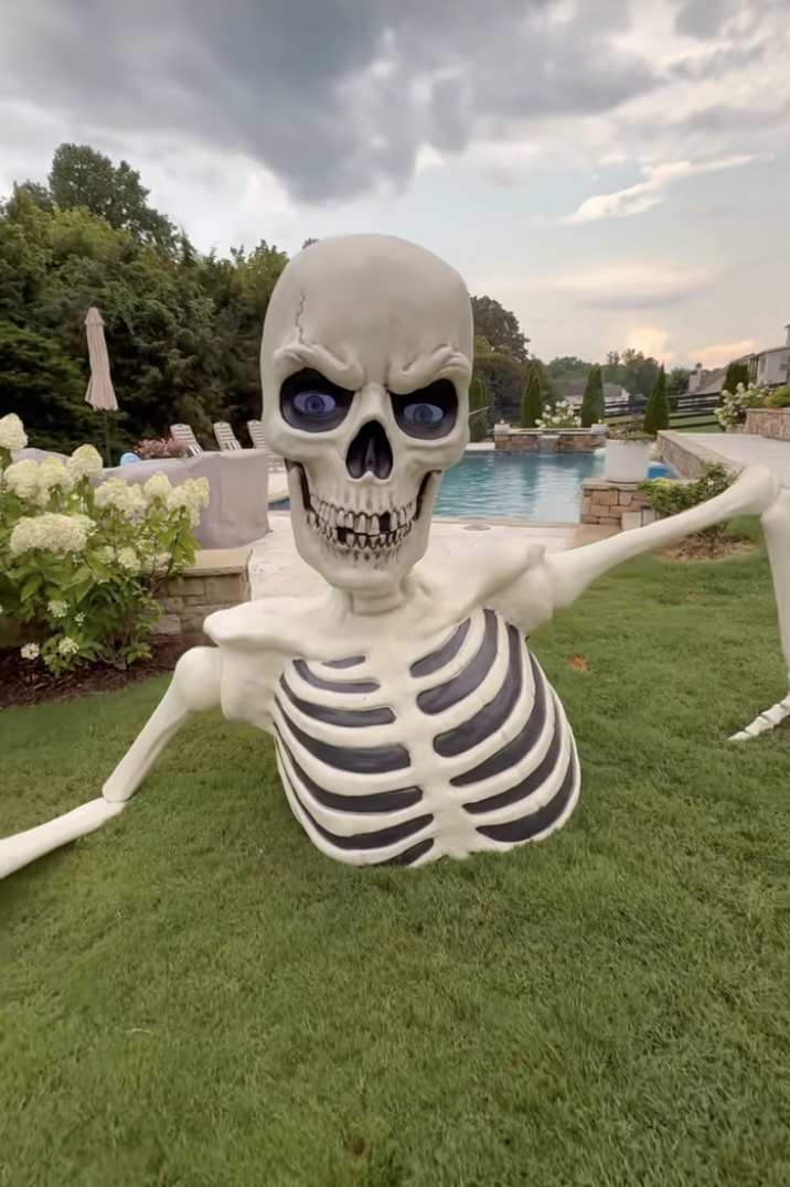 Huge ground-breaking skeleton decoration near pool - skeleton ideas for Halloween
