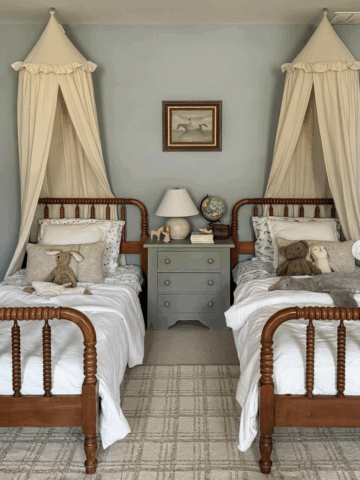 These rich wood spindle antique twin beds feature classic turned spindle posts, adding warmth and texture to this whimsical children’s bedroom. Draped canopy accents, a vintage-style globe, and soft neutral textiles create a timeless, storybook feel. Perfect for a traditional or English cottage–inspired space, these beds prove that antique twin frames can be both practical and magical.
