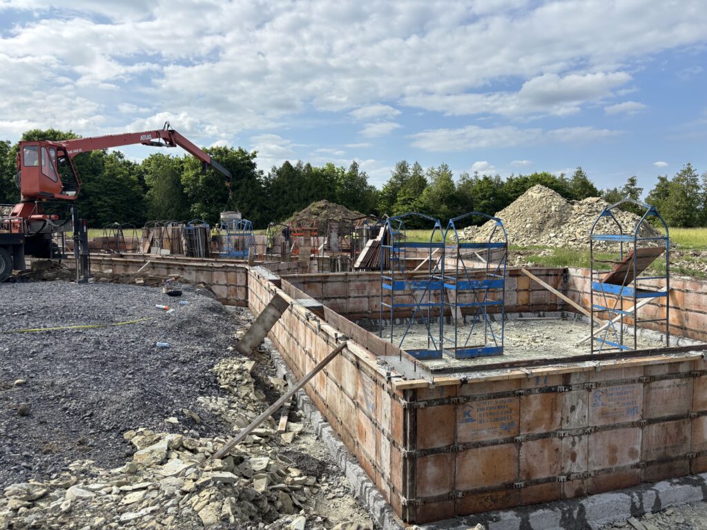 Framed foundation with concrete partially poured, showing progress of the slab-on-grade foundation.