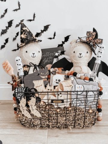 Halloween boo basket idea for kids featuring stuffed animal llamas, spooky treats, wooden ghost bags, and Halloween-themed pajamas.