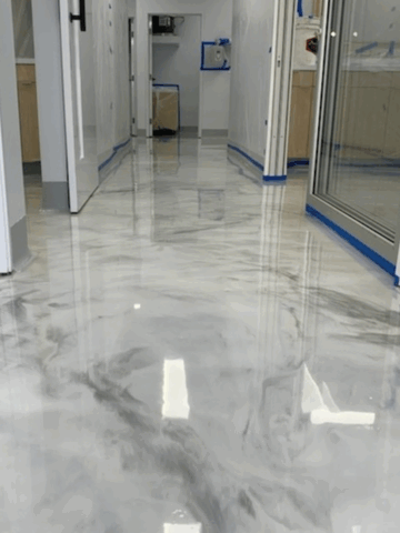 High-gloss metallic epoxy resin floor with gray and white swirls in a modern hallway under construction.