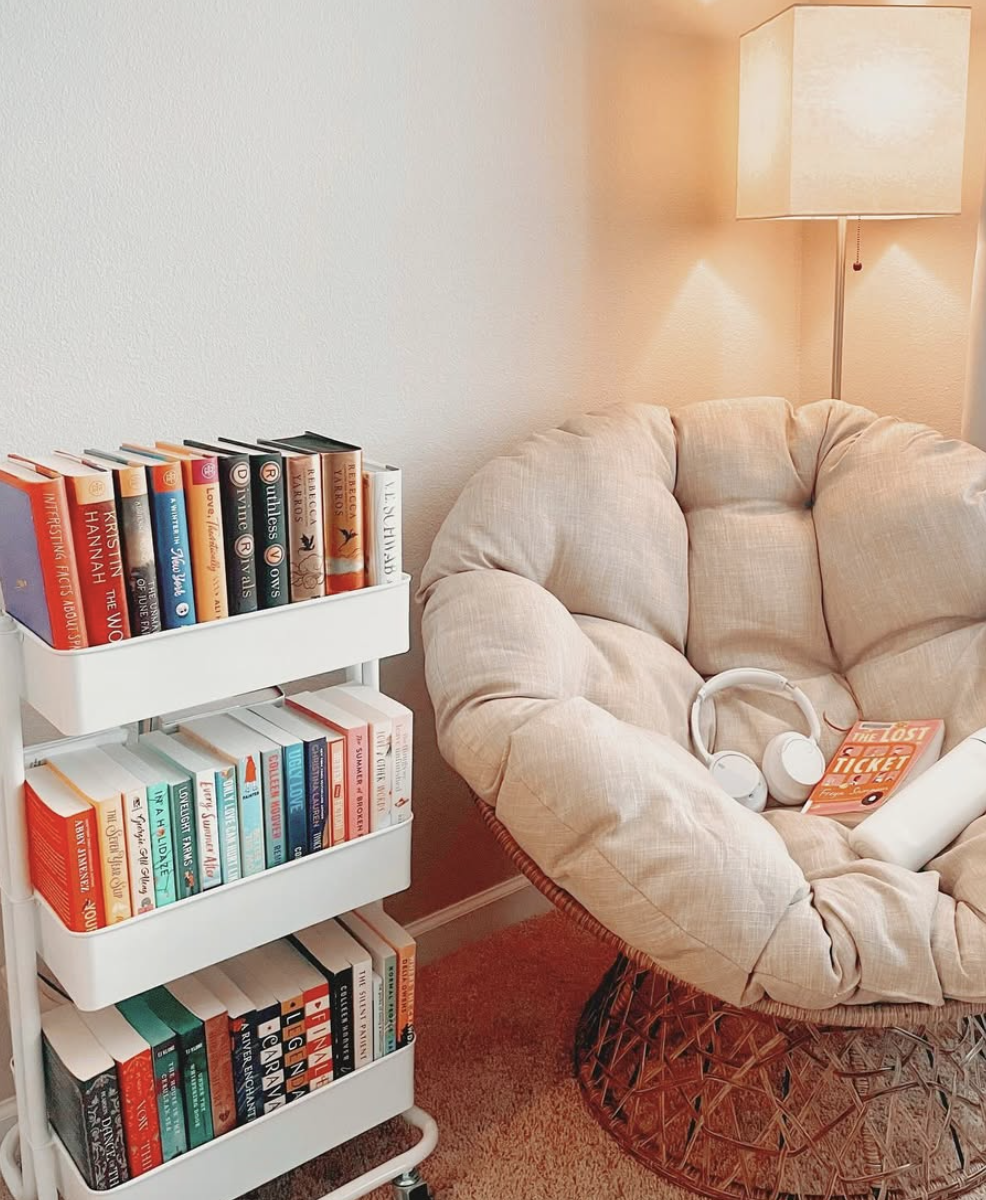 Cozy papasan chair reading nook with beige cushion, rolling book cart, floor lamp, and headphones