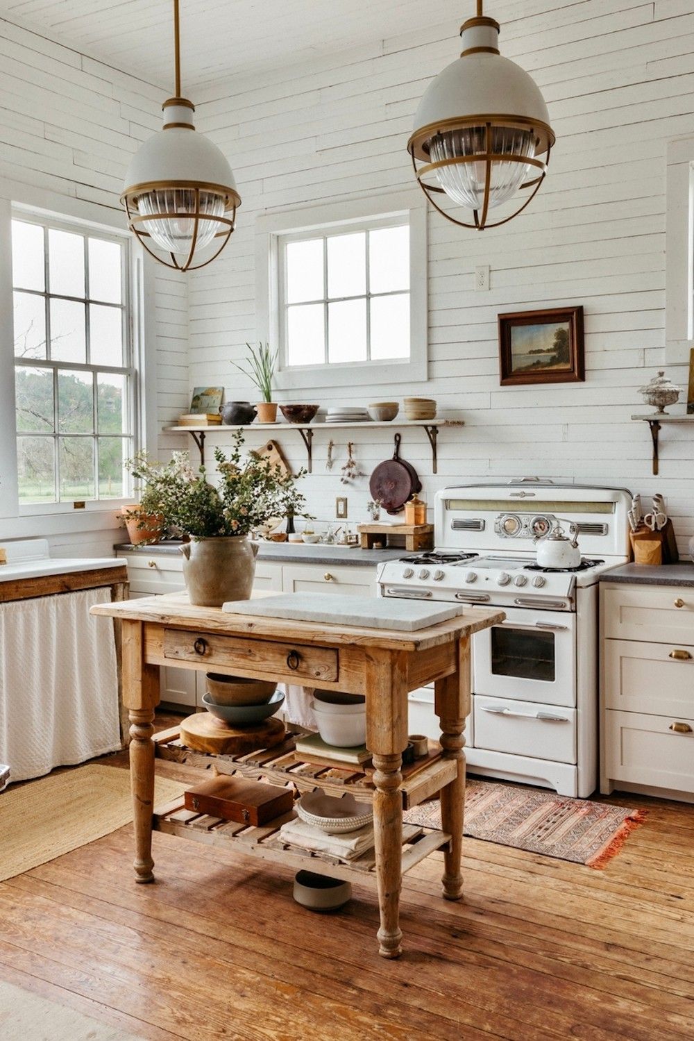 A charming grandmacore kitchen featuring a white vintage stove, rustic wooden island, open shelving with dishware, and cozy farmhouse details that create a nostalgic atmosphere.