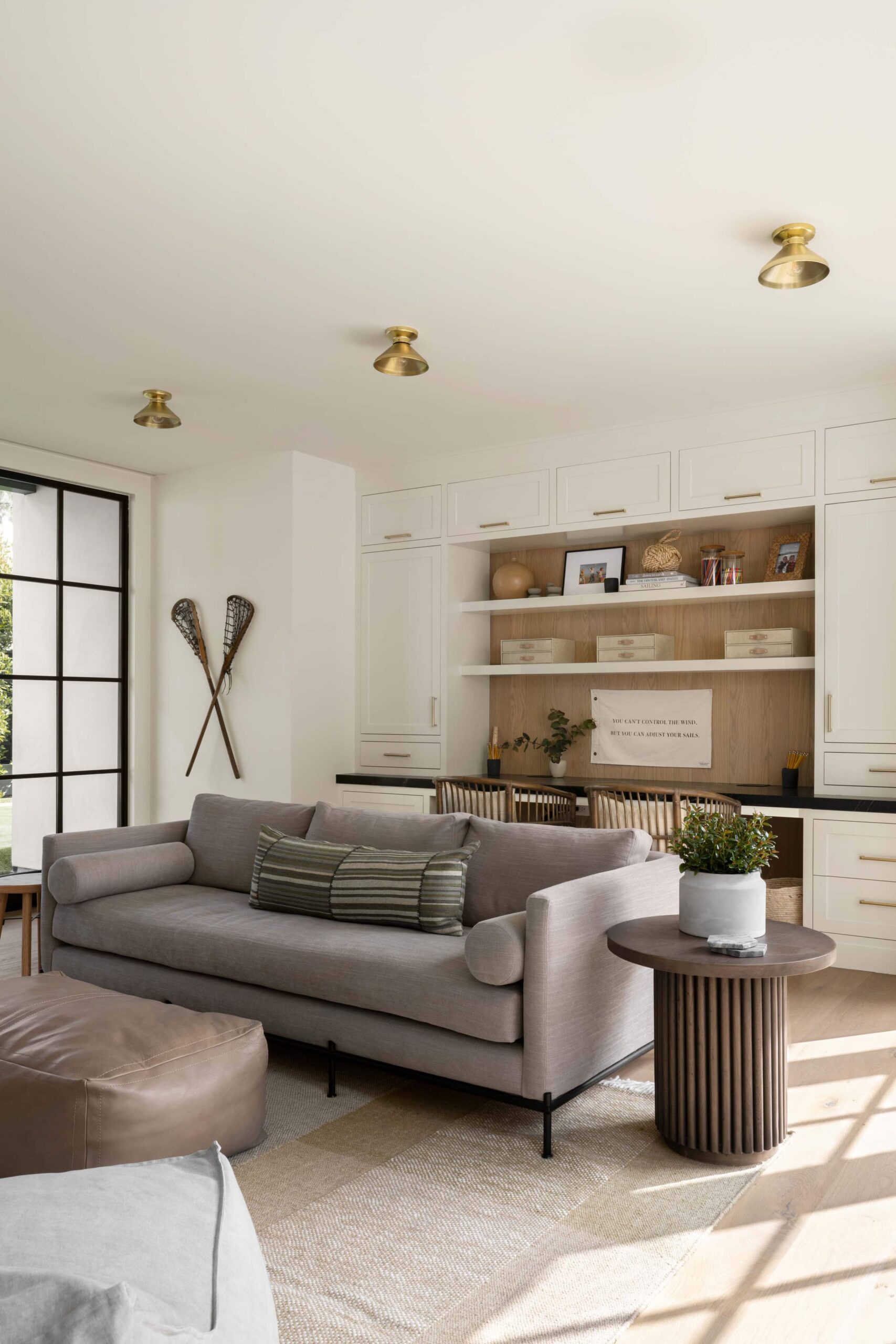 Studio McGee office with built-in double desk, white cabinetry, wood accents, and a cozy gray sofa in front.