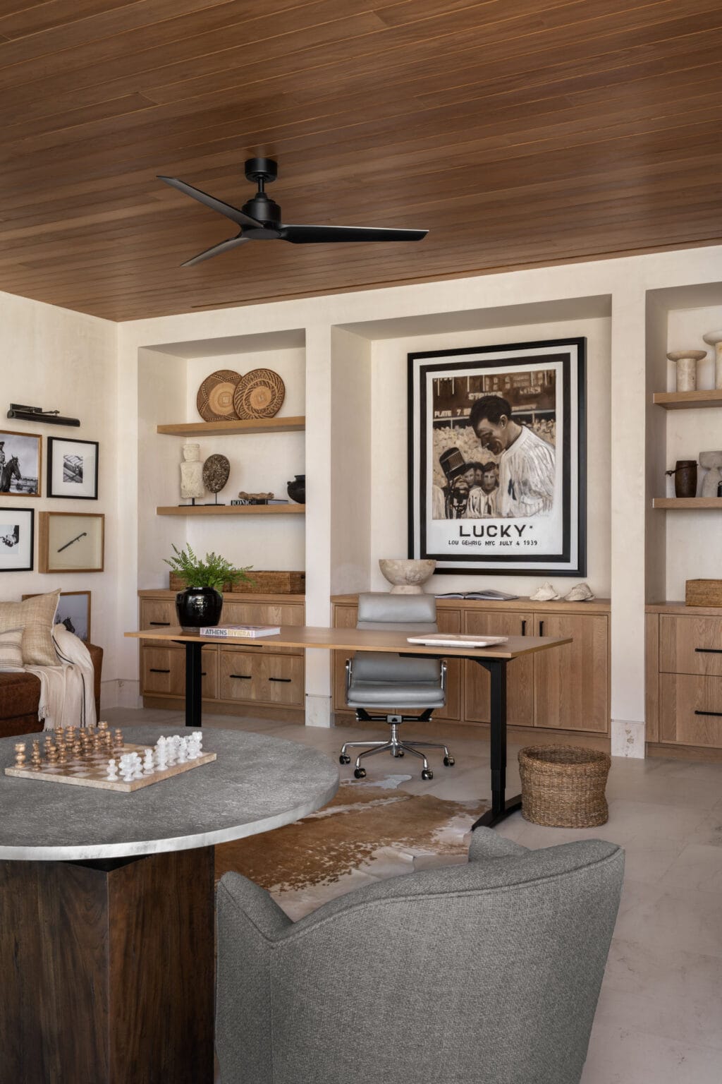 Studio McGee office with wood ceiling, built-in shelves, natural oak cabinetry, and a large framed artwork above the desk.