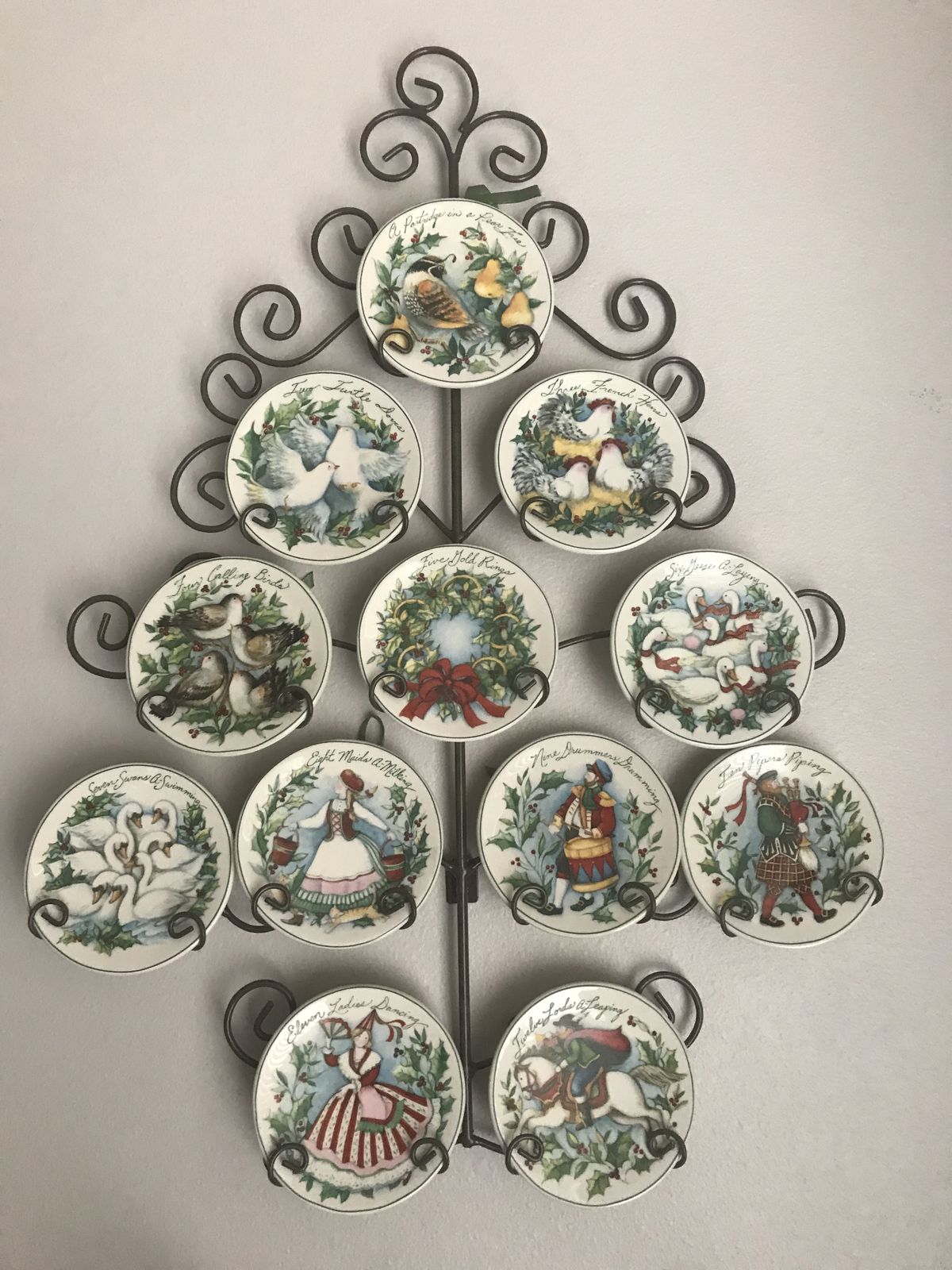 Christmas plate wall shaped like a tree with Twelve Days of Christmas collector plates on a decorative metal rack.