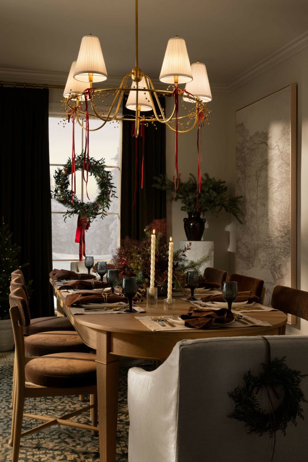 Studio McGee Christmas dining room with festive table setting, greenery wreath, red ribbon accents, and candlelit centerpiece.