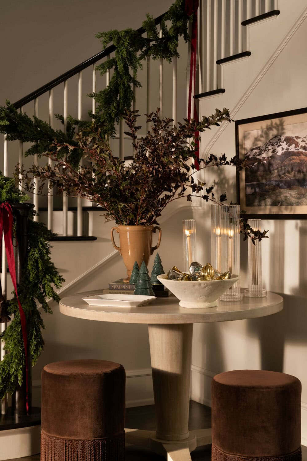 Studio McGee entryway decorated for Christmas with greenery garland on staircase, candles, and natural holiday accents.
