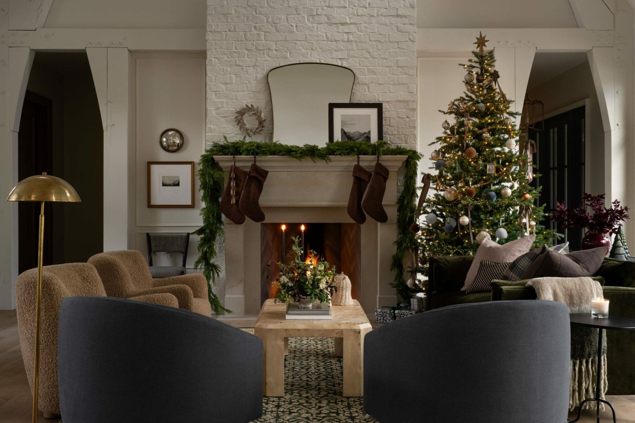 Studio McGee Christmas living room with decorated tree, fireplace garland, knit stockings, and cozy holiday accents.