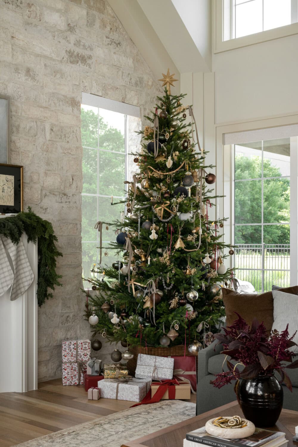 Studio McGee Christmas tree decorated with ribbons, metallic ornaments, natural accents, and wrapped gifts underneath.