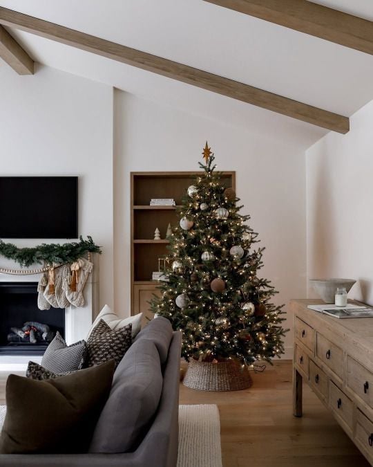 Christmas tree with a natural woven tree collar, warm white lights, and neutral ornaments styled in a cozy farmhouse living room.