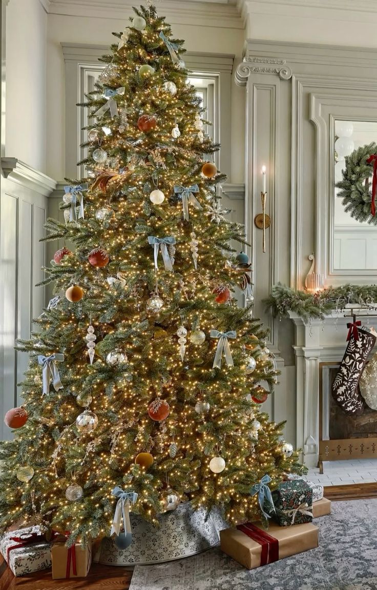 Christmas tree with a patterned metal tree collar, gold and blue ornaments, and warm twinkle lights for an elegant modern holiday style.