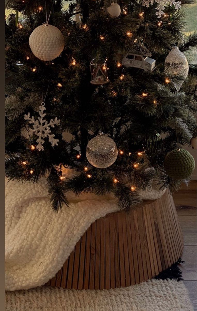 Christmas tree with a modern wood slat tree collar, neutral ornaments, and soft holiday lighting for a clean minimalist Christmas decor look.