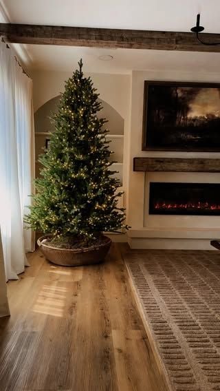 Christmas tree with a rustic wooden bowl style tree collar and warm white lights in a cozy farmhouse living room.