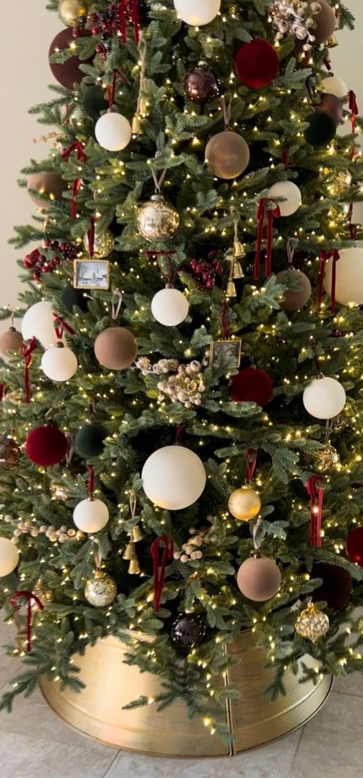 Christmas tree with a gold metal tree collar and warm-toned ornaments for a modern minimalist holiday style.