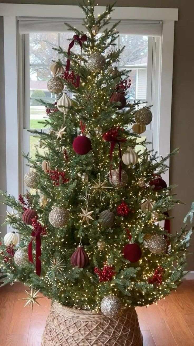Christmas tree with a woven tree collar base, red and gold ornaments, and warm lights creating a rustic farmhouse holiday decor look.